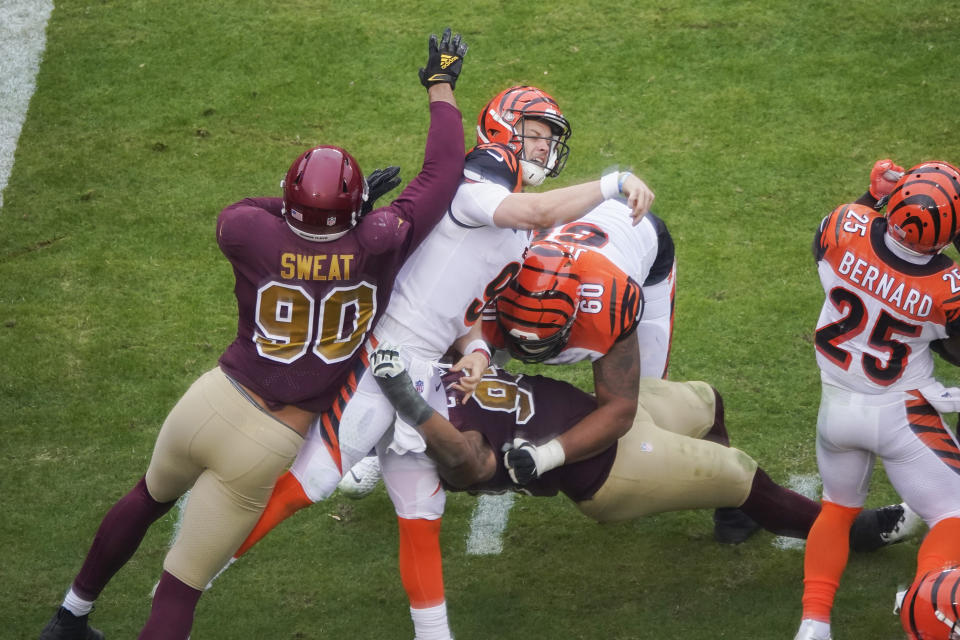 Cincinnati Bengals quarterback Joe Burrow (9) is hit and sandwiched inbetween Washington Football Team defensive end Montez Sweat (90), defensive tackle Jonathan Allen (93) and Cincinnati Bengals offensive guard Mike Jordan (60), during the second half of an NFL football game, Sunday, Nov. 22, 2020, in Landover, Md. After throwing a pass, Burrows was injured on this play and was carted off the field. (AP Photo/Al Drago)