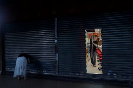 A man closes his shop as an anti-government protest passes, in Tsim Sha Tsui district, in Hong Kong