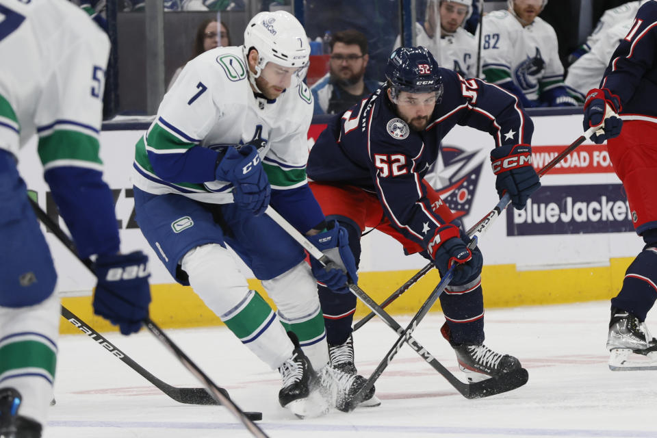 Vancouver Canucks' Carson Soucy, left, and Columbus Blue Jackets' Emil Bemstrom fight for the puck during the second period of an NHL hockey game Monday, Jan. 15, 2024, in Columbus, Ohio. (AP Photo/Jay LaPrete)