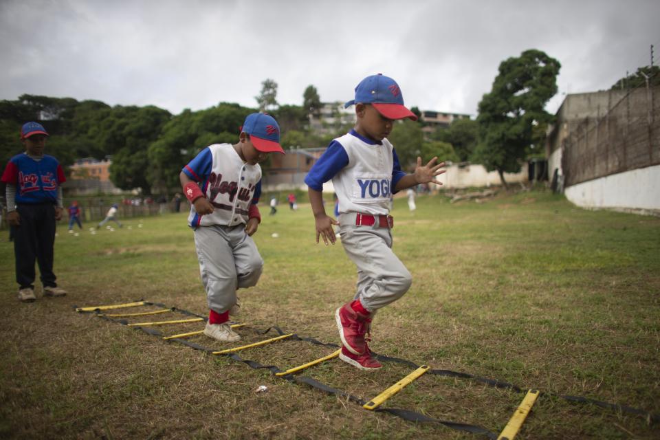 In this Aug. 12, 2019 photo, young baseball players perform ladder drills at Las Brisas de Petare Sports Center, in Caracas, Venezuela. "It's sad to see that the number of boys attending has dropped a lot," said 58-year-old trainer Nelson Castro, who has coached for decades. (AP Photo/Ariana Cubillos)