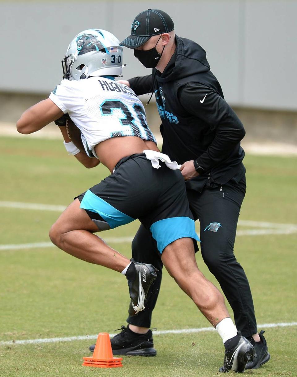 Carolina Panthers rookie running back Chuba Hubbard, left, continues to push himself upfield as offensive coordinator Joe Brady, right, attempts to strip the ball away during the teamÕs 2021 rookie minicamp practice on Friday, May 14, 2021.