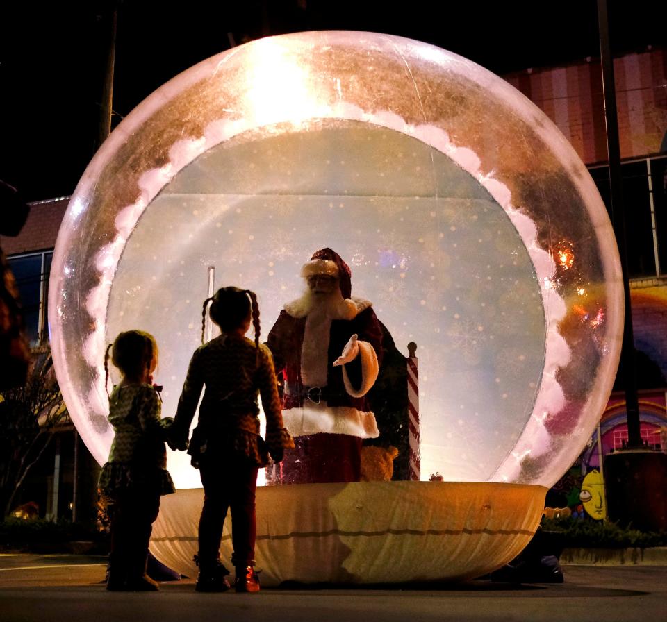Two girls approach a Santa in a giant inflatable snow globe during the 2020 Automobile Alley's Lights on Broadway.