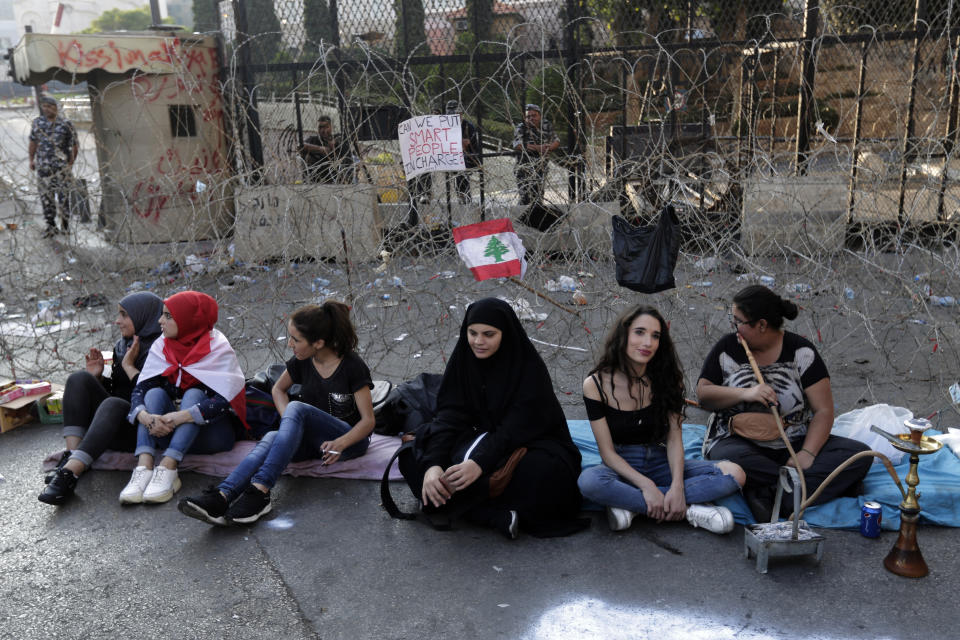 Anti-government protesters sit in front of a barbed-wire barrier on a road that leads to the Government House, during a protest in Beirut, Lebanon, Tuesday, Oct. 22, 2019. Prime Minister Saad Hariri briefed western and Arab ambassadors Tuesday of a reform plan approved by the Cabinet that Lebanon hopes would increase foreign investments to help its struggling economy amid wide skepticism by the public who continued in their protests for the sixth day. (AP Photo/Hassan Ammar)
