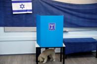 A dog stands next to it's owner behind a voting booth as Israelis vote in a parliamentary election at a polling station in Rosh Ha'ayin, Israel