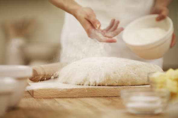 Woman dusting dough with flour