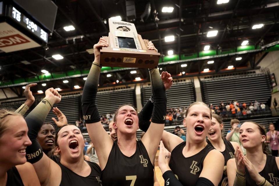 Lone Peak’s Zoey Burgess hoists the trophy as the team celebrates its win over Skyridge in the 6A girls volleyball state championship in November 2023.