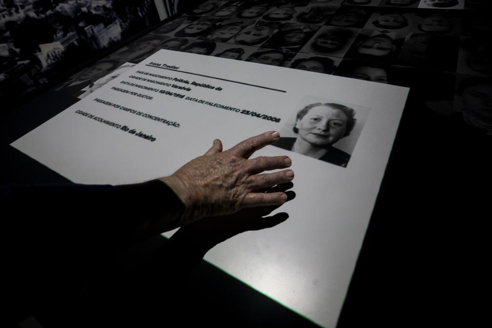 Jorge Tredler, 83, of Poland, who came to Brazil with his family in Feb. 1951 after taking refuge in Russia and other countries during the second World War, points to a photo of his mother Irena on an interactive table that tells the stories of thousands of people who took refuge in Brazil during the Holocaust, at the Holocaust Victims Memorial on its opening day to the public in Rio de Janeiro, Brazil, Thursday, Jan. 19, 2023. (AP Photo/Bruna Prado)