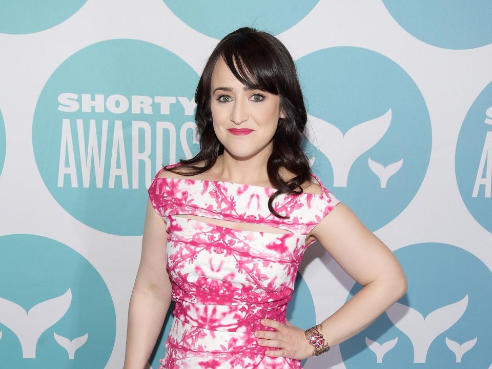 Mara Wilson posing with her hand on her hip while wearing a pink sleeveless pink and white dress.