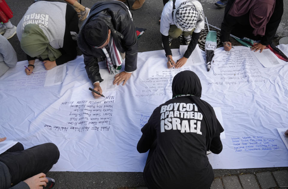 Pro-Palestinian supporters write names of lives lost in the war, as they protest outside Parliament in Cape Town, South Africa, Tuesday, Nov. 21, 2023. The majority of MP's voted to close the Israeli embassy in South Africa over the war in Gaza. (AP Photo/Nardus Engelbrecht)