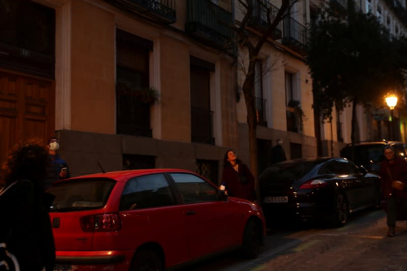 Passerbiers stop to listen to Spanish blues singer "Betta" sing from her balcony during a daily evening concert to support health workers and to make it easier for her neighbours to bear the coronavirus lockdown in Madrid