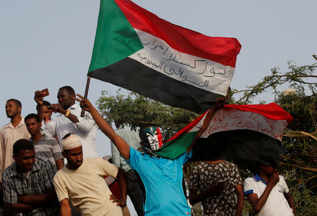 A protester holding a Sudanese flag and wearing a Guy Fawkes mask takes part in a demonstration in front of the Defence Ministry in Khartoum, Sudan April 17, 2019. REUTERS/Umit Bektas