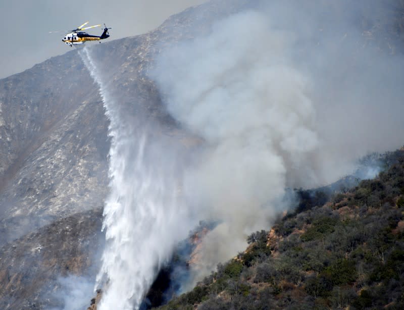 Firefighters battle a blaze from the air that was threatening homes in the Pacific Palisades community of Los Angeles, California, U.S.