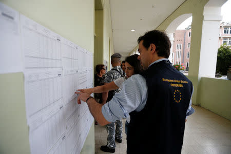 A member of the European Union Election Observation Mission and a woman look at a voter's registry list in a polling station during the parliamentary election in Beirut, Lebanon, May 6, 2018. REUTERS/Jamal Saidi