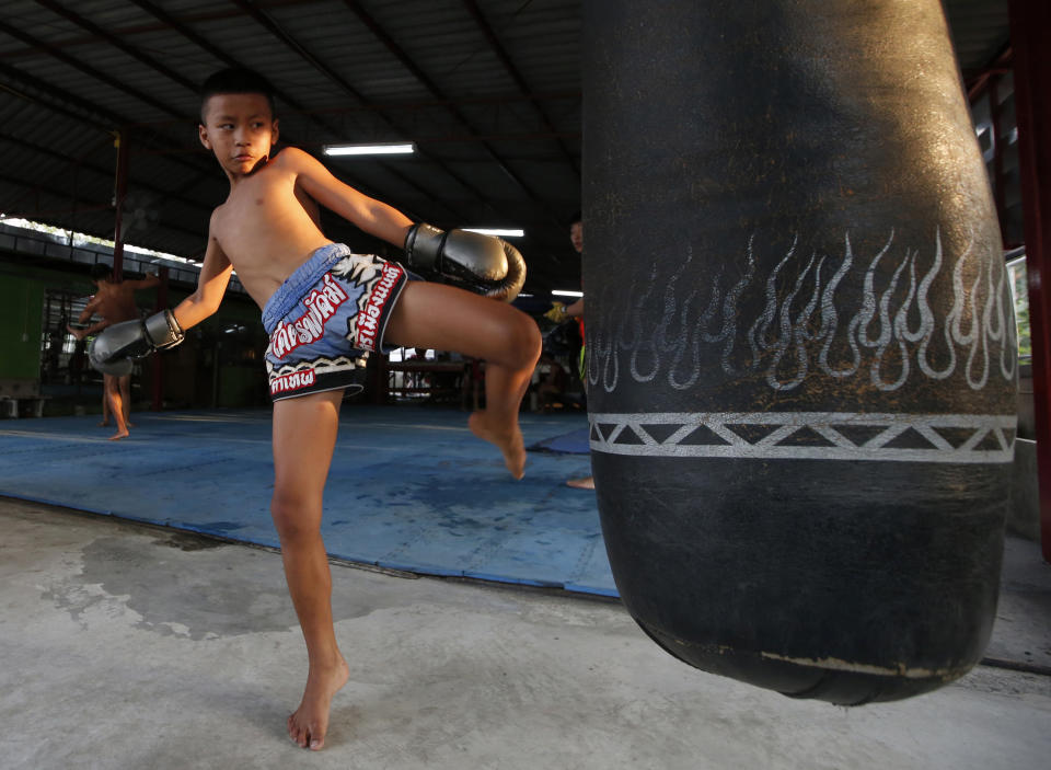 In this Wednesday, Nov. 14, 2018, photo, Thai kickboxer Chaichana Saengngern, 10-years old, practices kicks at a training camp in Bangkok, Thailand. Thai lawmakers recently suggested barring children younger than 12 from competitive boxing, but boxing enthusiasts strongly oppose the change. They say the sport is part of Thai culture and gives poor families the opportunity to raise a champion that will lift their economic circumstances. (AP Photo/Sakchai Lalit)