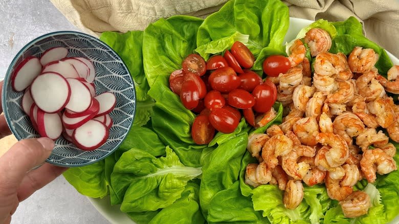 assembling salad with shrimp on platter