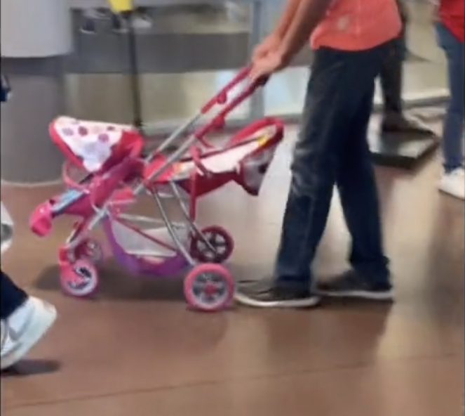 A student pushing a light-colored stroller that can hold two small children