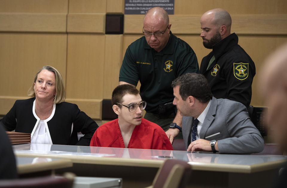 Florida school shooting defendant Nikolas Cruz speaks with attorney Gabe Ermine in Judge Elizabeth Scherer's courtroom at the Broward County Courthouse, Thursday, Dec. 19, 2019, in Fort Lauderdale, Fla. The trial of Parkland school shooting defendant Nikolas Cruz was delayed Thursday until at least next summer, when he will face a death penalty case stemming from the February 2018 massacre that left 17 people dead. (Michael Laughlin/South Florida Sun-Sentinel via AP, Pool)