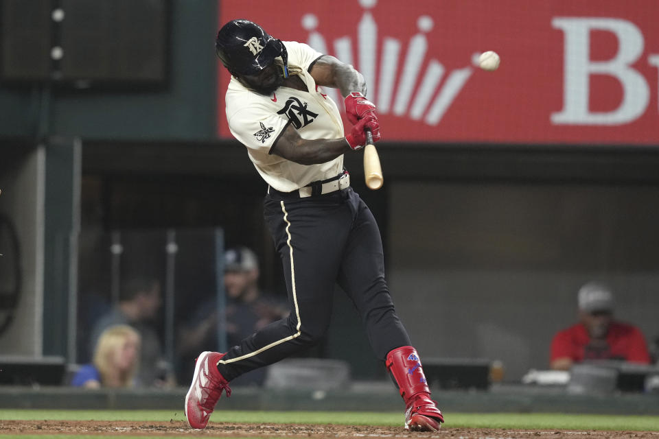 Texas Rangers' Adolis Garcia hits a two-run home run during the fourth inning of a baseball game against the Colorado Rockies in Arlington, Texas, Friday, May 19, 2023. Rangers' Nathaniel Lowe also scored on the play. (AP Photo/LM Otero)