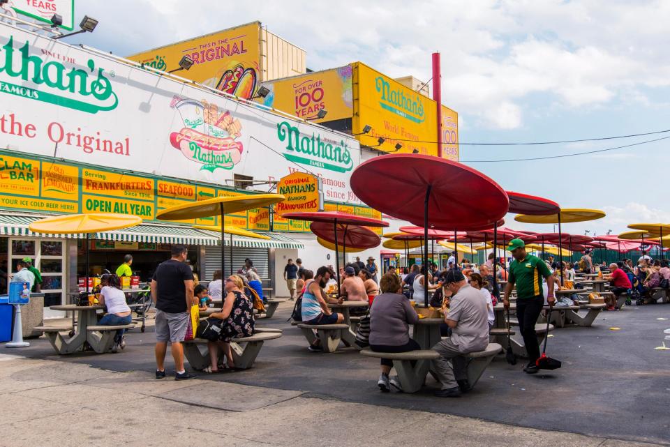 The outside of Nathan's Famous restaurant diners eating at tables outdoors