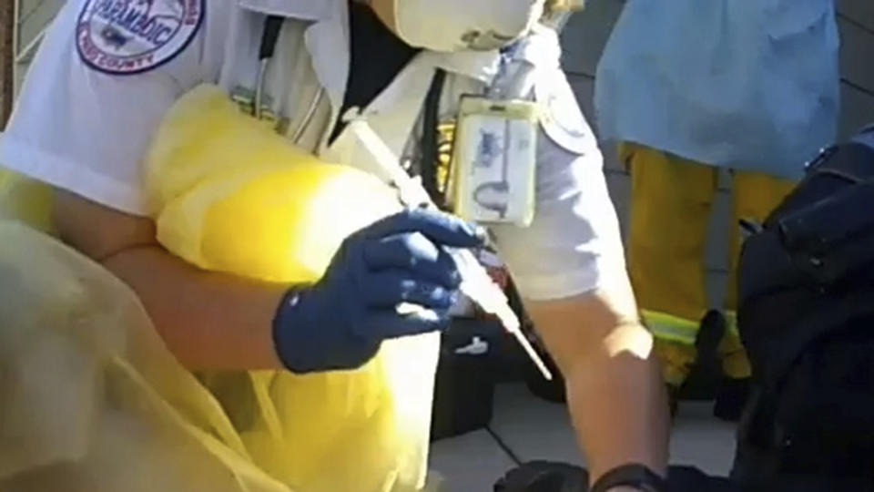 In this image from Colorado Springs Police Department body-camera video, a paramedic prepares to inject ketamine as police restrain Hunter Barr outside his father's home in Colorado Springs, Colo., on Sept. 25, 2020. Retired postal worker Mark Barr had called 911 for help controlling his son, who he said wasn't violent but was having a bad reaction to LSD. He watched as a medic gave two injections. His son was dead within hours. "I couldn't figure out why that was necessary," he said of the second injection. (Colorado Springs Police Department via AP)