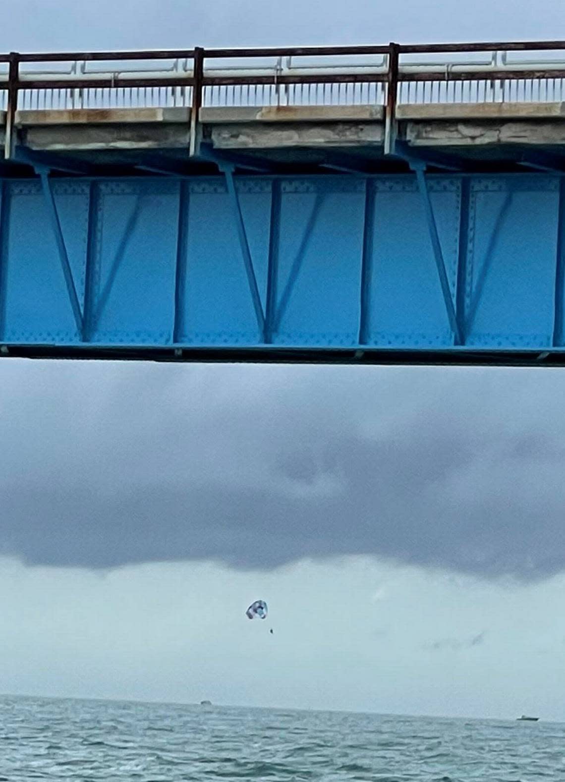 Three people hang from a parasail off the old Seven Mile Bridge in the Florida Keys Monday, May 30, 2022, minutes before a high wind gust prompted the captain of the boat towing them to cut them loose.