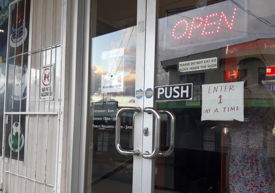 A store with a sign saying only one customer at a time in Suva, Fiji, Thursday, June 24, 2021. A growing coronavirus outbreak in Fiji is stretching the health system and devastating the economy. It has even prompted the government to offer jobless people tools and cash to become farmers.(AP Photo/Aileen Torres-Bennett)