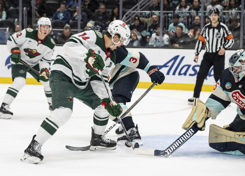 Minnesota Wild forward Joel Eriksson Ek, left, shoots against Seattle Kraken goalie Joey Daccord, right, during the first period of an NHL hockey game, Saturday, Feb. 24, 2024, in Seattle. (AP Photo/Stephen Brashear)