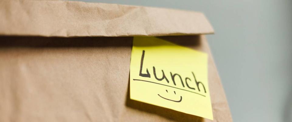 Craft paper bag with funny yellow sticker. Ecological food bag for lunch or food take away delivery, closeup, copy space