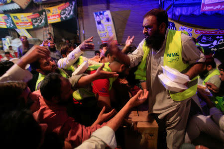 A worker of Mohammad Yaqoob Sheikh, nominated candidate of political party, Milli Muslim League (MML), distributes food packs to the residents, during an election campaign for the National Assembly NA-120 constituency in Lahore, Pakistan September 9, 2017. Picture taken September 9, 2017. REUTERS/Mohsin Raza
