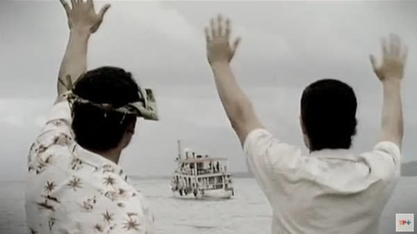 two people waving down a boat