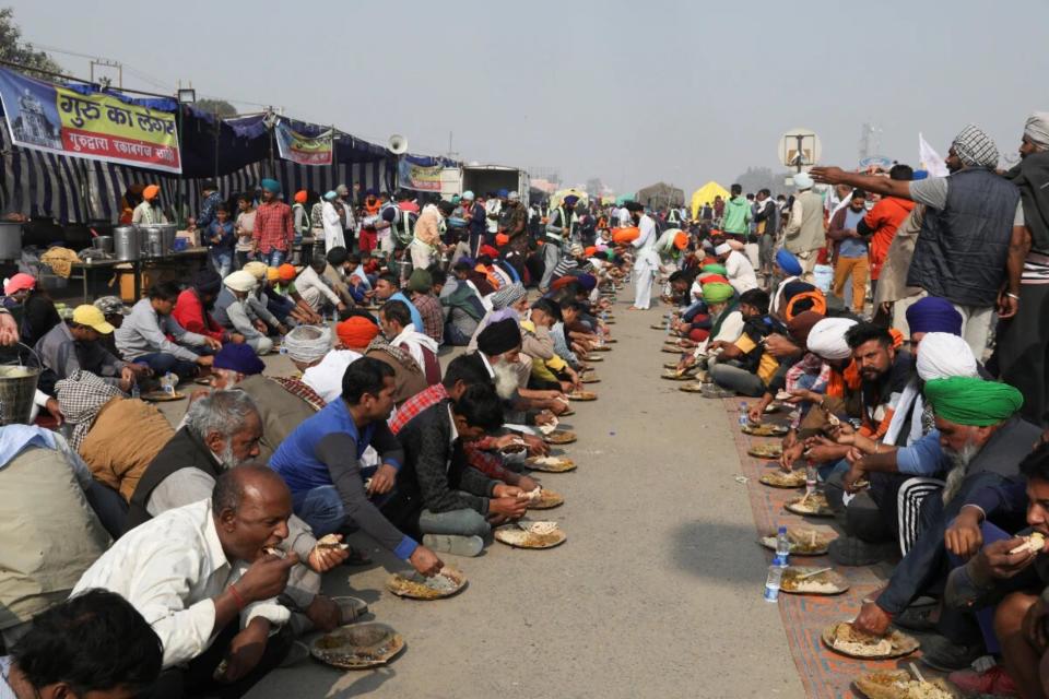 Varias personas reparten comida a los agricultores que permanecen asentados en Singhu, a las afueras de Nueva Delhi. (Foto: Anushree Fadnavis / Reuters).