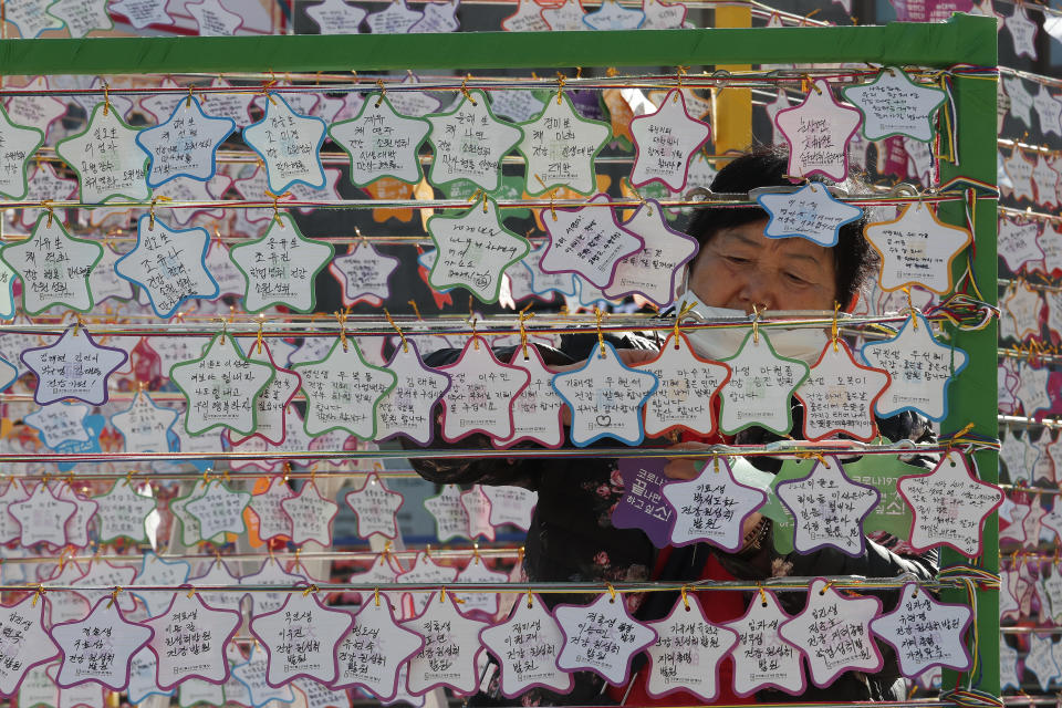 A woman hangs on a paper note to wish for her child's success in the college entrance exams at the Jogyesa Buddhist temple in Seoul, South Korea, Thursday, Dec. 3, 2020. Hundreds of thousands of masked students in South Korea, including 35 confirmed COVID-19 patients, took the highly competitive university entrance exam Thursday despite a viral resurgence that forced authorities to toughen social distancing rules. (AP Photo/Ahn Young-joon)