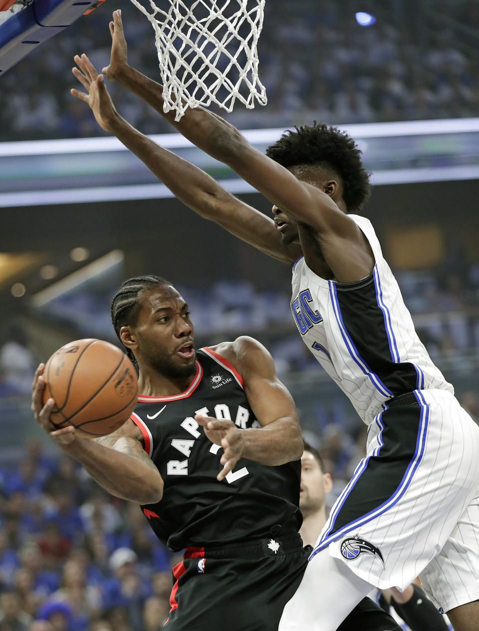 Toronto Raptors' Kawhi Leonard, left, passes the ball around Orlando Magic's Jonathan Isaac during the first half in Game 3 of a first-round NBA basketball playoff series, Friday, April 19, 2019, in Orlando, Fla. (AP Photo/John Raoux)