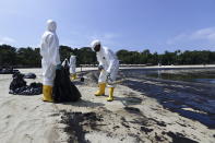 Workers clean oil spill along Sentosa's Tanjong Beach area in Singapore, Sunday, June 16, 2024. (AP Photo/Suhaimi Abdullah)