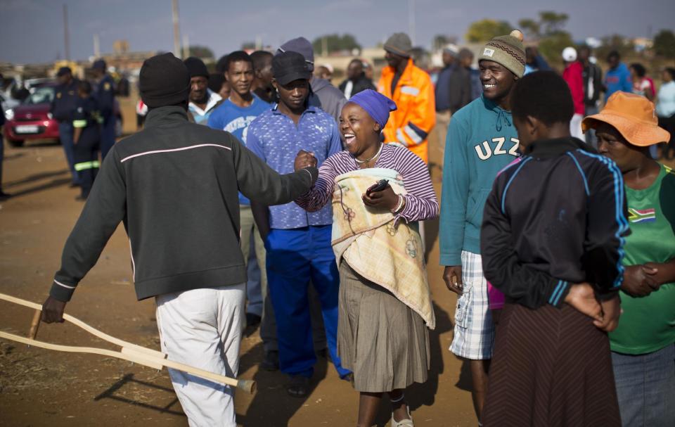 A South African woman jokes with a friend who tried to jump the queue by pretending to need crutches but was caught out, at a polling station that was burned down overnight but a tent was erected to vote in the morning, in the politically-sensitive mining town of Bekkersdal, South Africa Wednesday, May 7, 2014. (AP Photo/Ben Curtis)