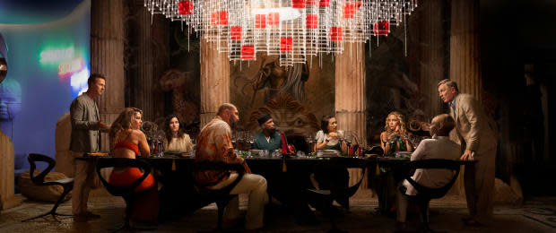 In a still from "Glass Onion: A Knives Out Mystery," Daniel Craig as Benoit Blanc interrogates party guests at a table. The guests are played by stars including Edward Norton, Dave Bautista, Mary J. Blige, Kathryn Hahn. Madelyn Cline, Kate Hudson, Leslie Odom Jr., Janelle Monáe and Jessica Henwick.<p>Netflix</p>