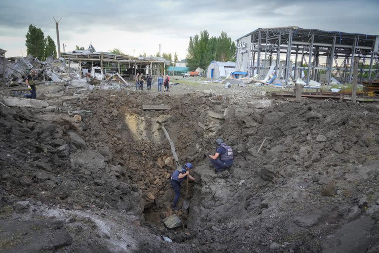 Policías inspeccionan un cráter causado por un proyectil ruso en Pokrovsk, en la región de Donetsk, en Ucrania, el 15 de junio de 2022. (AP Foto/Efrem Lukatsky)