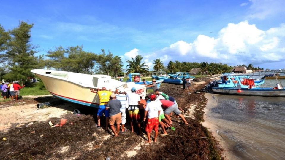 pescadores sacan sus botes del agua en Cancún.