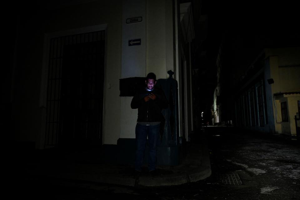 A man uses his cell phone on a street in Havana during a blackout on Tuesday, Sept. 27, 2022.