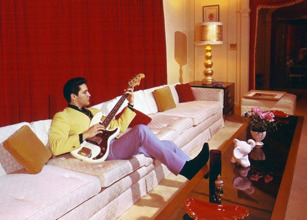 Elvis Presley fiddles with an electric bass inside Graceland, his Memphis mansion, in 1965.