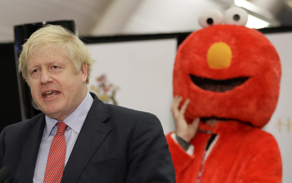 Bobby Smith, a political and fathers' rights activist and founder and leader of the 'Give Me Back Elmo' party watches as Britain's Prime Minister and Conservative Party leader Boris Johnson speaks after the Uxbridge and South Ruislip constituency count declaration at Brunel University in Uxbridge, London, Friday, Dec. 13, 2019. (AP Photo/Kirsty Wigglesworth)