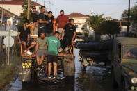 Local residents use a tractor to cross the flooded town of Palamas, near Karditsa, Thessaly region, central Greece, Friday, Sept. 8, 2023. Rescue crews in helicopters and boats are plucking people from houses in central Greece inundated by tons of water and mud after severe rainstorms caused widespread flooding. (AP Photo/Vaggelis Kousioras)
