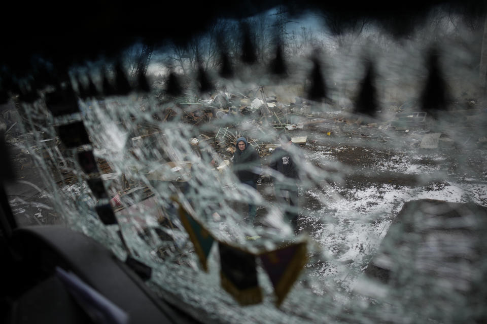 Men are seen through a smashed window of a damaged truck following a rocket attack in Kyiv, Ukraine, Thursday, Jan. 26, 2023. (AP Photo/Daniel Cole)