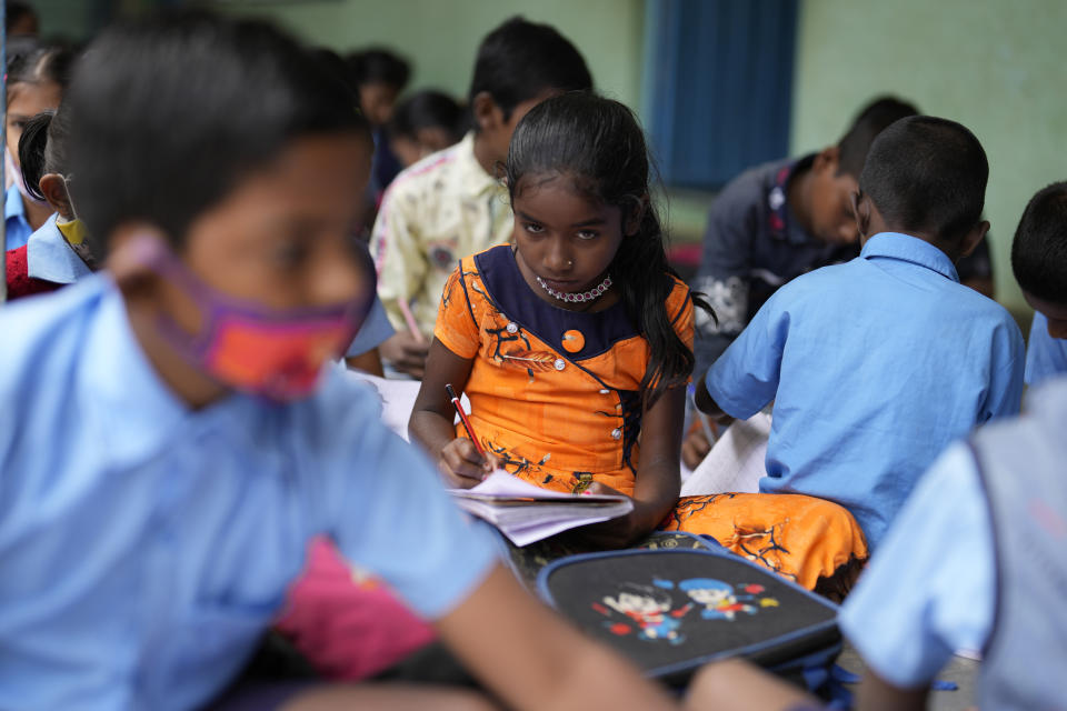 Jerifa Islam writes Kannada language lessons in her notebook at a government school in Bengaluru, India, Wednesday, July 20, 2022. A flood in 2019 in the Darrang district of India's Assam state started Jerifa, her brother Raju and their parents on a journey that led the family from their Himalayan village to the poor neighborhood. (AP Photo/Aijaz Rahi)