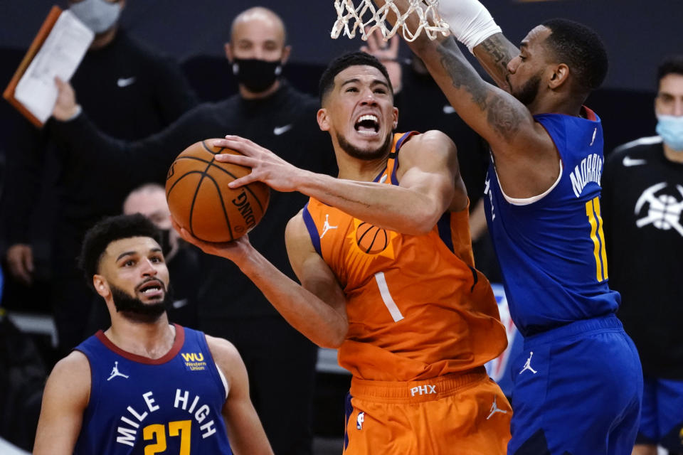 Phoenix Suns guard Devin Booker (1) drives between Denver Nuggets guard Jamal Murray and Monte Morris (11) during the second half of an NBA basketball game Friday, Jan. 22, 2021, in Phoenix. (AP Photo/Rick Scuteri)