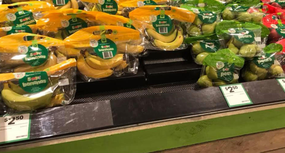 Bananas and other fruit wrapped in plastic pictured on a Woolworths shelf.