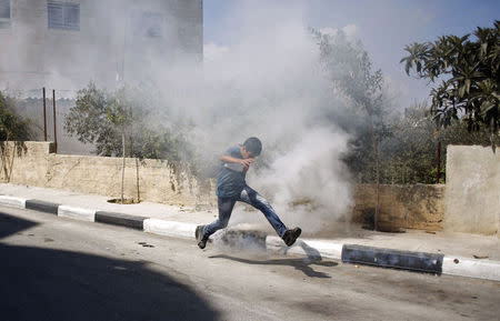 A Palestinian man kicks a tear gas canister fired by Israeli soldiers, during clashes following the funeral of Issa al Qitri, in the West Bank city of Ramallah September 10, 2014. REUTERS/Mohamad Torokman