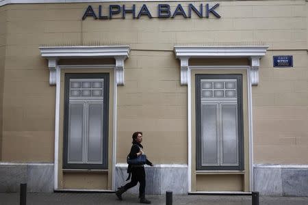 A woman makes her way past the logo of Alpha Bank in Athens March 26, 2014. REUTERS/Yorgos Karahalis