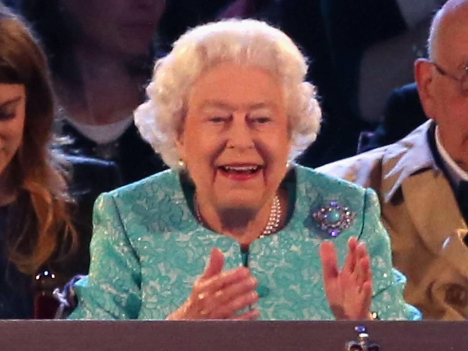 Queen Elizabeth smiles and claps at a performance