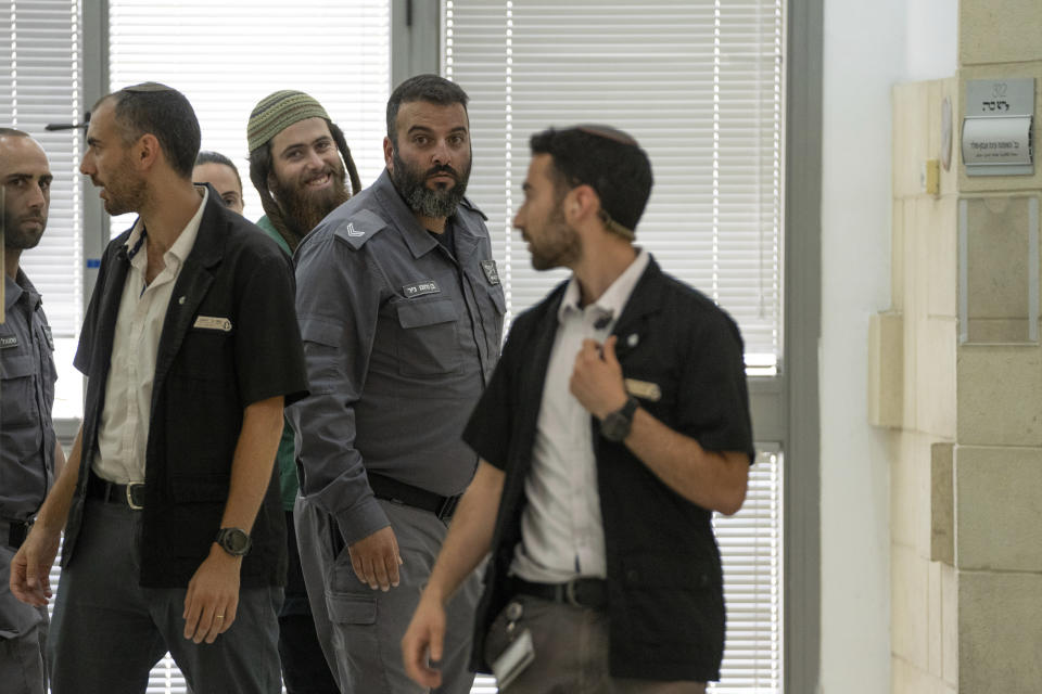 Elisha Yered, 22, center is led handcuffed by officers during an appearance at the Jerusalem District Court on Tuesday, Aug. 8, 2023. Yered is one of two Israeli settlers arrested on suspicion of involvement in the killing of a Palestinian man in the West Bank on Friday. (AP Photo/Ohad Zwigenberg)